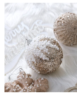 Detail of champagne gold Christmas balls and pearl snowflake ornaments on white plush