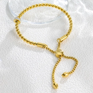 Detail of twisted cable gold bracelet with sparkling zircon ring and adjustable slider clasp