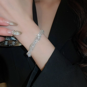 Close-up of a silver twisted rhinestone bracelet worn over a black blazer sleeve