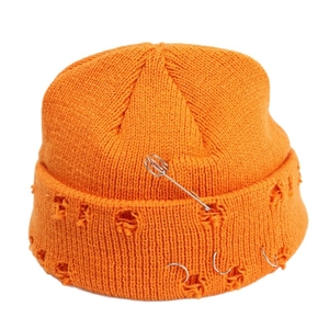 Orange distressed knit beanie with metal pin and ring accents on a white background