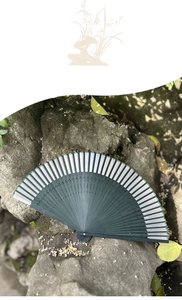Detail of green Chinese folding fan with hollow bamboo ribs on a natural mossy rock