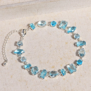 Bracelet élégant en argent avec pierres bleues de formes variées sur fond textile beige