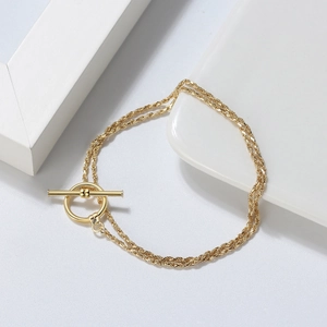 Detail view of a double-layered gold twisted rope chain bracelet with a classic OT clasp