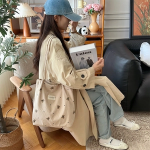 Close-up of beige corduroy tote bag featuring detailed bear and heart embroidery