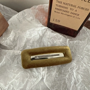Macro detail of olive green velvet rectangular hair clip with silver metal interior