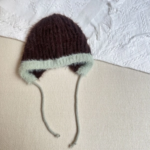 Detail of plush winter trapper hat showing soft two-tone fleece and knit earflap straps