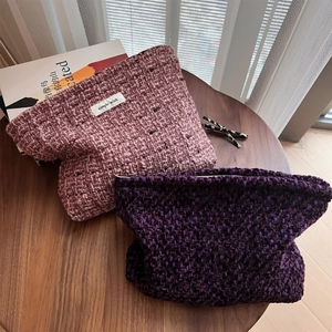 Detailed close-up of textured tweed makeup bags in soft pink and purple on a wooden table