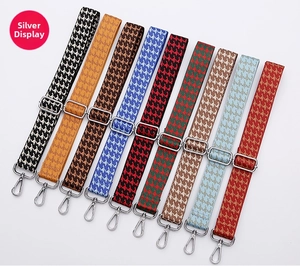 Detailed view of adjustable houndstooth bag straps with silver metal hardware clips