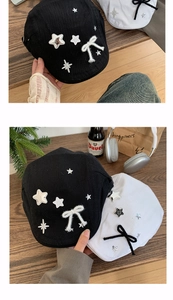 Close-up of black and white newsboy hats with silver stars and delicate ribbon bows