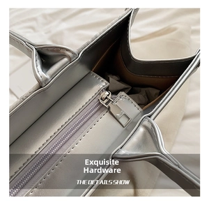 Close-up of the smooth silver metal zipper and dark brown lining on a tote bag