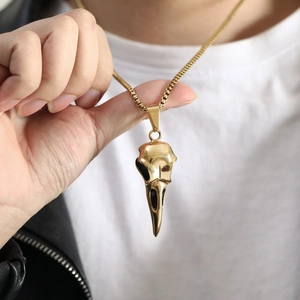 Detailed view of a gold eagle skull pendant on a box chain for men's fashion jewelry