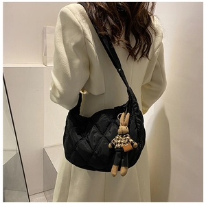 Detail of black quilted dumpling bag with chic lattice stitching and cute rabbit charm