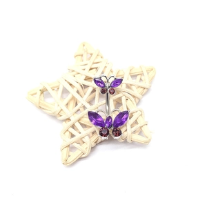 Shiny silver butterfly belly ring with purple and red gemstones on a star prop