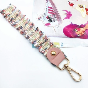 Detail of colorful woven tassel bag strap with pink leather and golden metal clasp