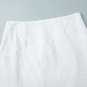 Detail of white textured fabric with natural crinkle effect and soft pleat finish