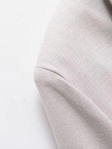 Close-up of light grey woven fabric texture and stitching on a short blazer jacket