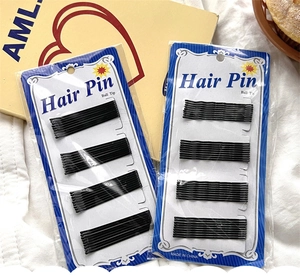 Close-up of black metal bobby pins with ball tip safety design on paper cards