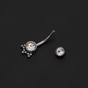 Macro detail of curved belly button ring with silver metal and clear cubic zirconia stones