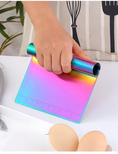 Close-up of hand holding iridescent stainless steel dough scraper with measurement scales
