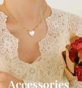 Close-up of heart-shaped white shell pendant with gold paperclip chain on model