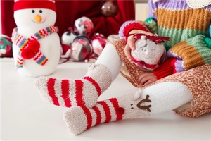 Close-up of children's thick coral fleece Christmas socks with festive red stripes and 3D antlers