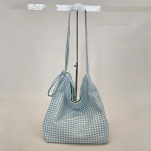 Detail of blue and white gingham canvas hobo bag showing tied knot shoulder strap design