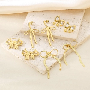 Close-up of 18K gold bow earrings set with sparkling zircon on textured stone base