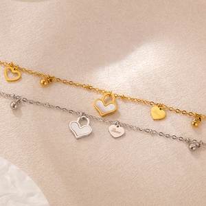 Detail von Gold- und Silber-Herzarmbändern mit Perlmutt und Love-Gravur-Elementen