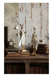 Close-up of Victorian style resin rabbit figurines with intricate gold floral details