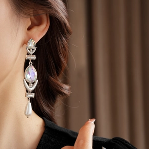 Close-up of elegant silver tassel earrings with pearls and crystals worn by a model
