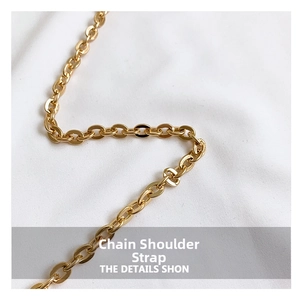 Close-up of polished gold metal chain strap on white fabric for shell crossbody bag
