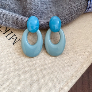 Detailed close-up of retro oval acrylic dangle earrings with blue marble texture on canvas