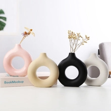 Set of four donut-shaped ceramic vases in pink, beige, black, and white colors