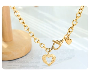 Detail of gold heart pendant necklace with chunky chain link and toggle clasp