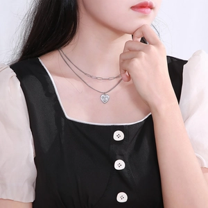 Close-up of silver double-layered necklace with heart pendant and paperclip chain style