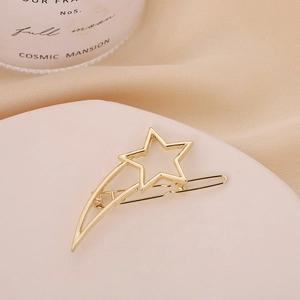 Elegant gold hollow star and comet tail metal hair clip on a white ceramic tray