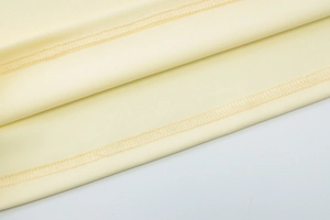 Macro detail of high-quality double-needle stitching on yellow mesh fabric dress