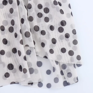 Close-up of lightweight polka dot mesh fabric with layered hem detail on the dress
