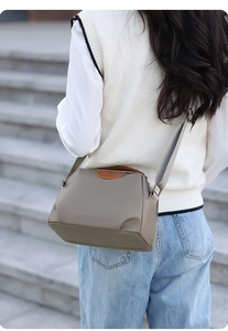 Detail of taupe waterproof nylon crossbody bag with adjustable strap and leather trim