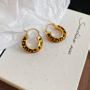 Detail of 14k gold plated earrings with leopard print enamel on brand packaging