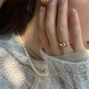 Close-up of S925 sterling silver knotted ring on finger with elegant knit background