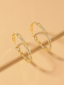 Detailed close-up of golden hoop earrings featuring paved rhinestones on warm background