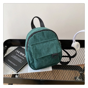 Detailed texture of dark green corduroy mini backpack with flap pocket and metal D-ring