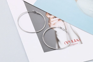 Detailed view of silver hoop earrings with twisted rope texture and pin closure