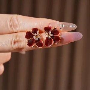 Vintage style gold earrings with dark red enamel flower petals and zircon centers