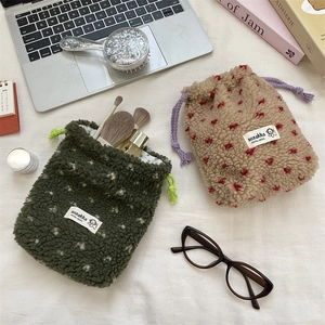 Detail of plush heart drawstring pouches in green and beige for travel cosmetic storage