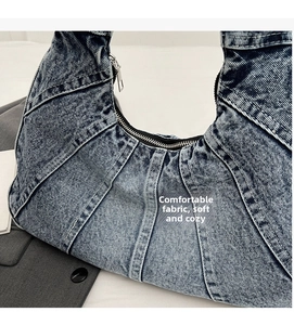 Gros plan du sac porté épaule en denim bleu avec coutures patchwork et fermeture éclair argentée