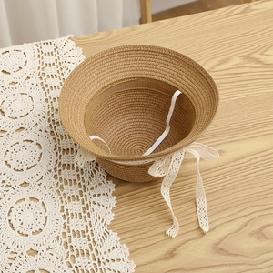Detail of straw hat texture with white lace bow and elastic chin strap on wooden surface
