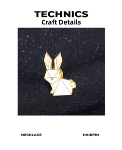 Detail of white geometric rabbit brooch with gold trim on dark textured fabric