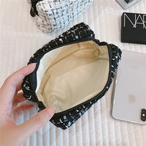 Interior view of small tweed makeup bag showing beige lining and spacious storage
